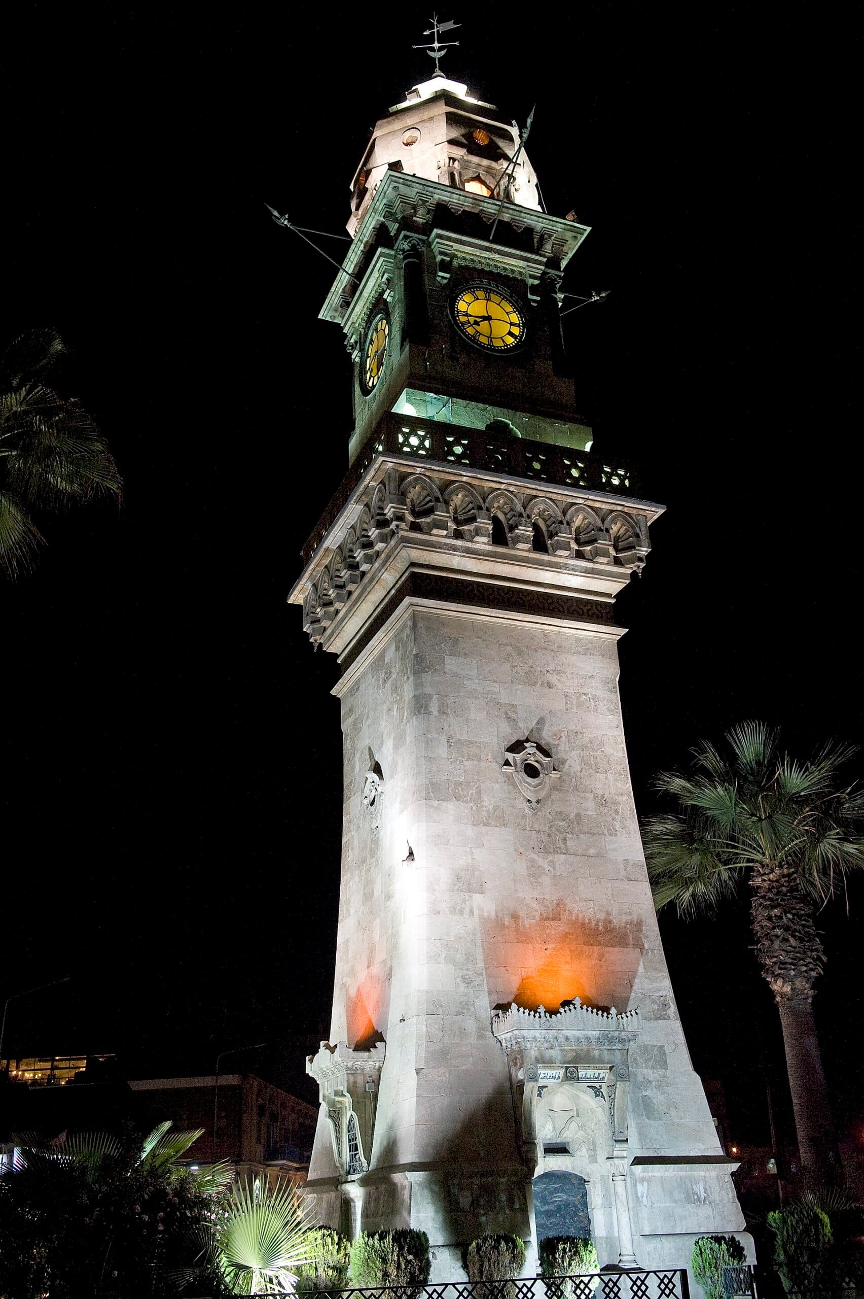 Bab el-Ferec Saat Kulesi gece aydınlatmasında; sarı kadranlar, mukarnaslı şerefe ve tepedeki rüzgâr oku