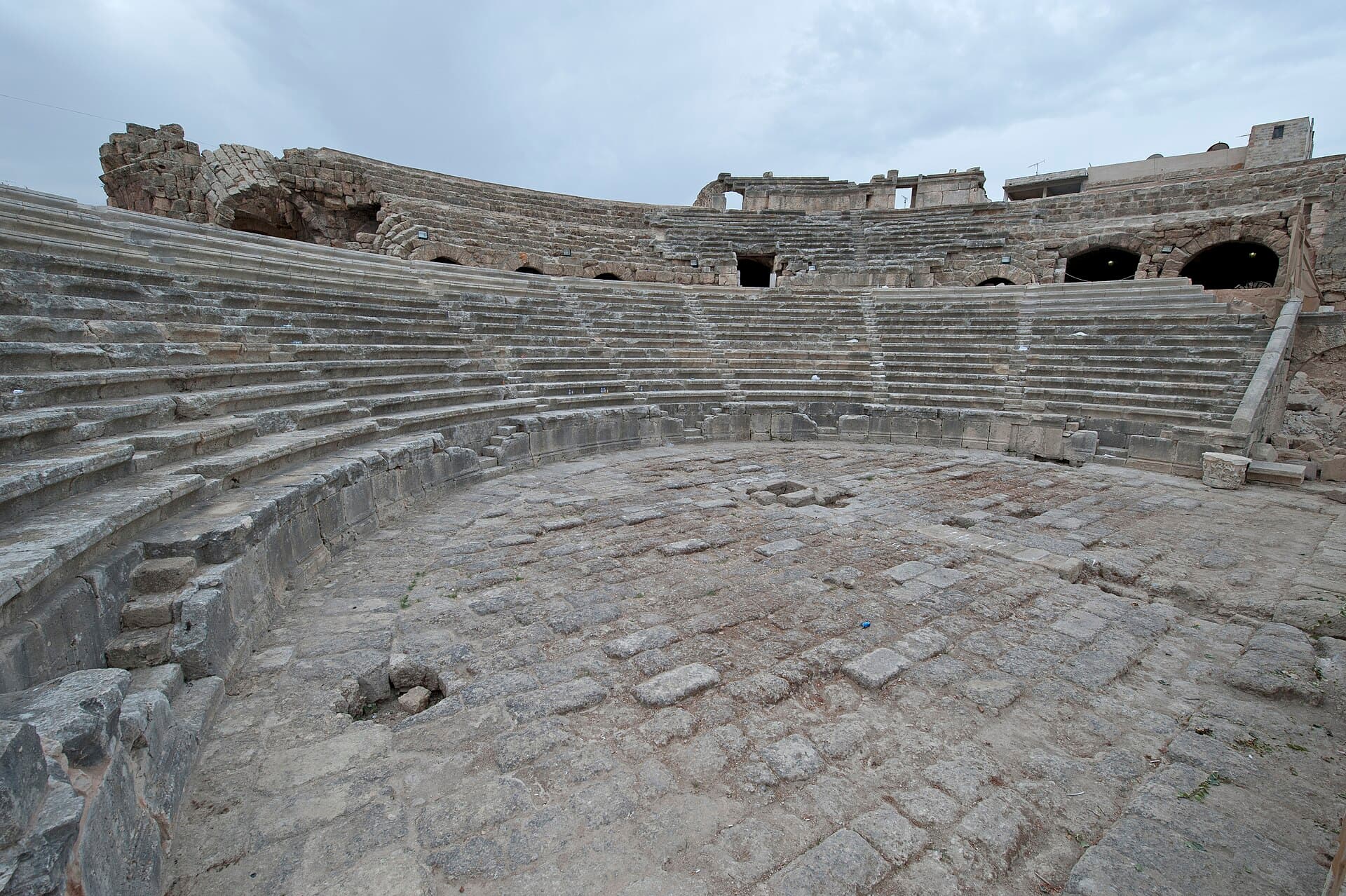 Cebele Roma Tiyatrosu'nun taş oturma basamakları, orkestra zemini ve arkadaki kemerli geçitler
