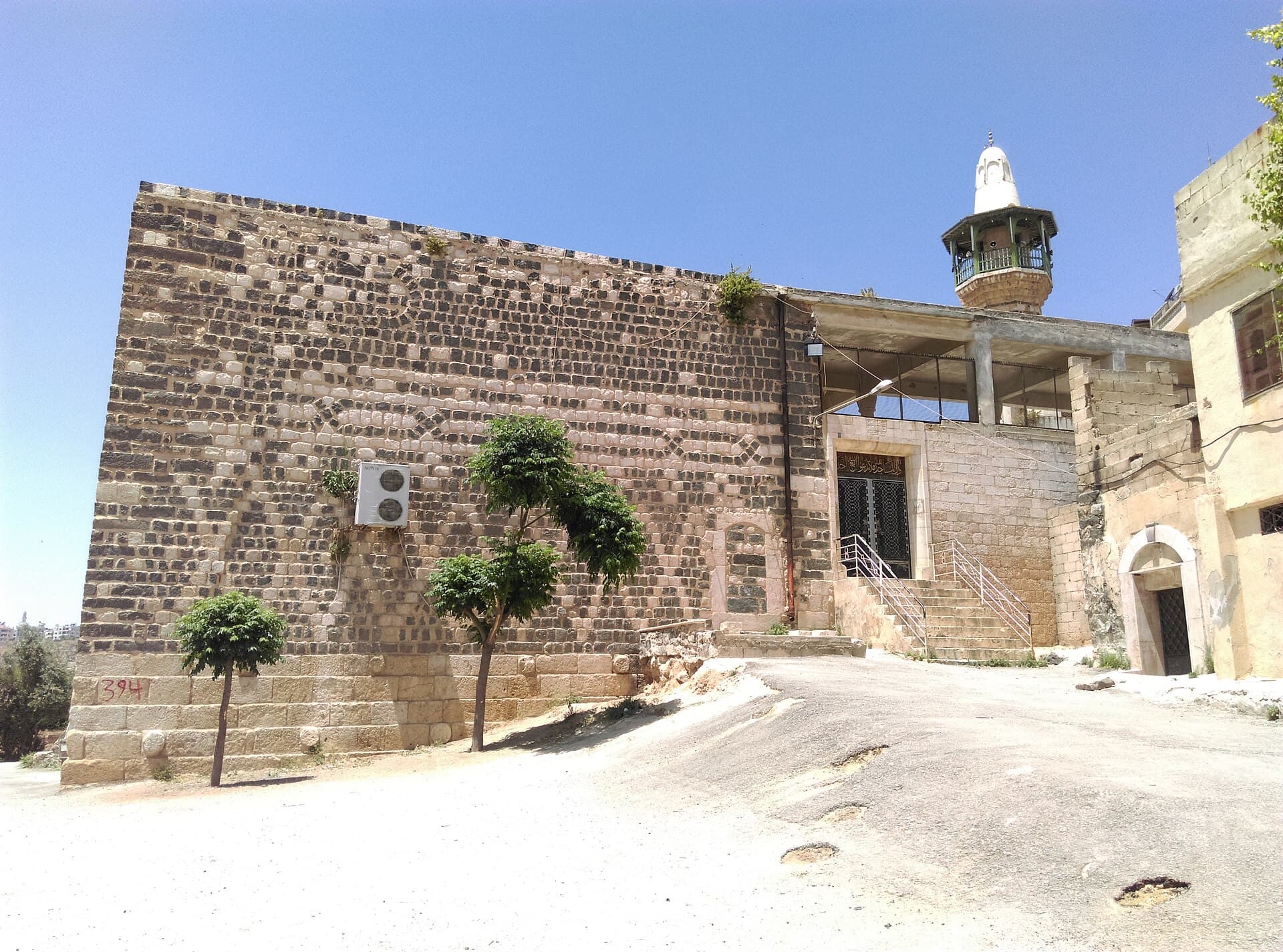 Ebu'l-Feda Camii'nin siyah bazalt ve beyaz kireçtaşı örgülü cephesi; sağda tek şerefeli minare