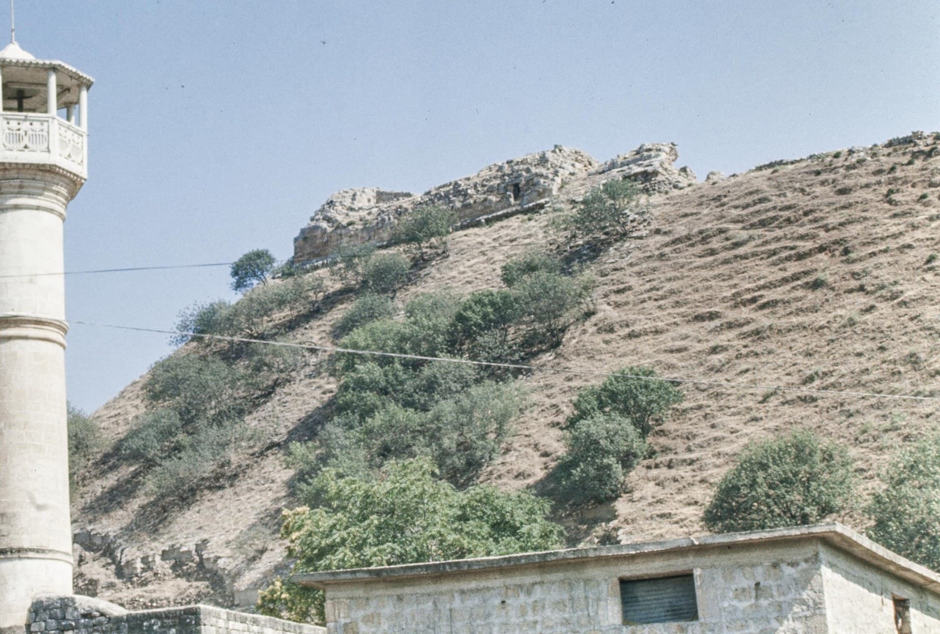 Harim Kalesi'nin höyük tepesindeki duvar kalıntıları; solda kasabanın beyaz minaresi