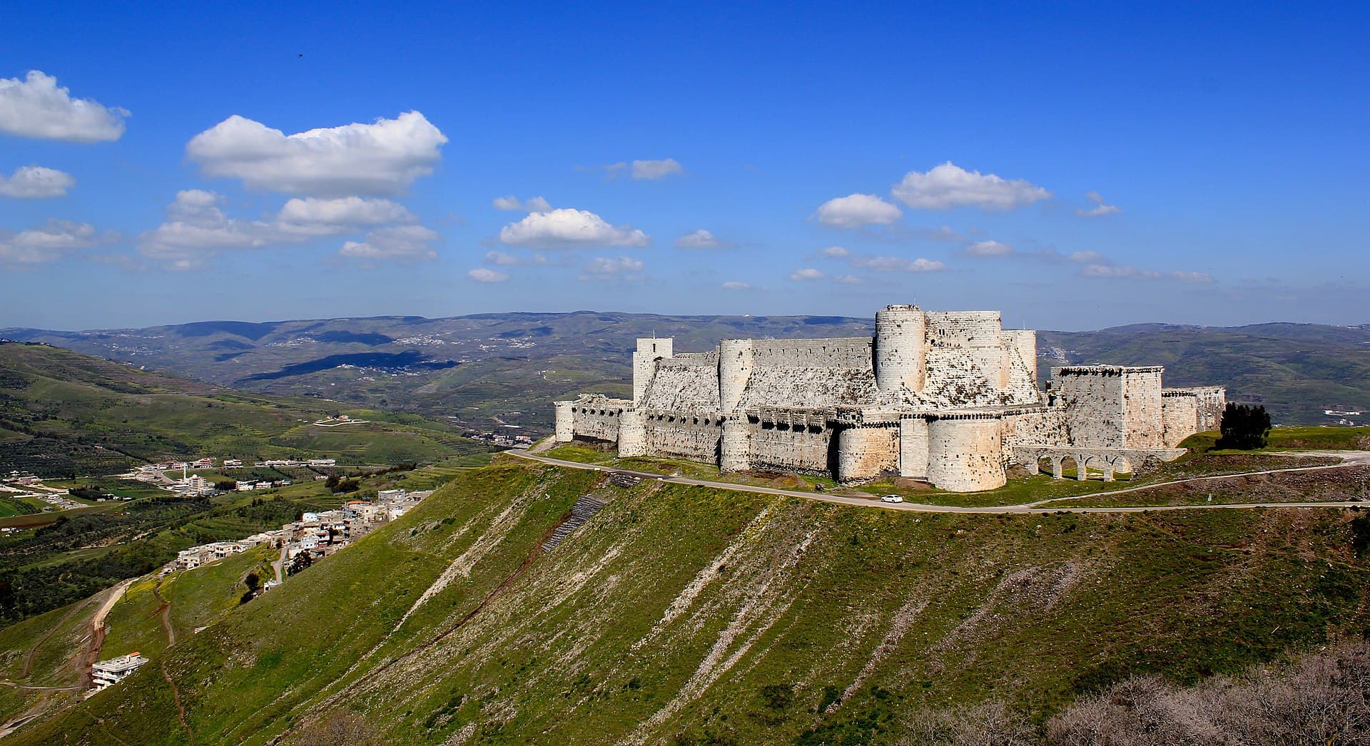 Krak des Chevaliers, yeşil tepelerin üzerinde çift surlu genel görüntüsüyle