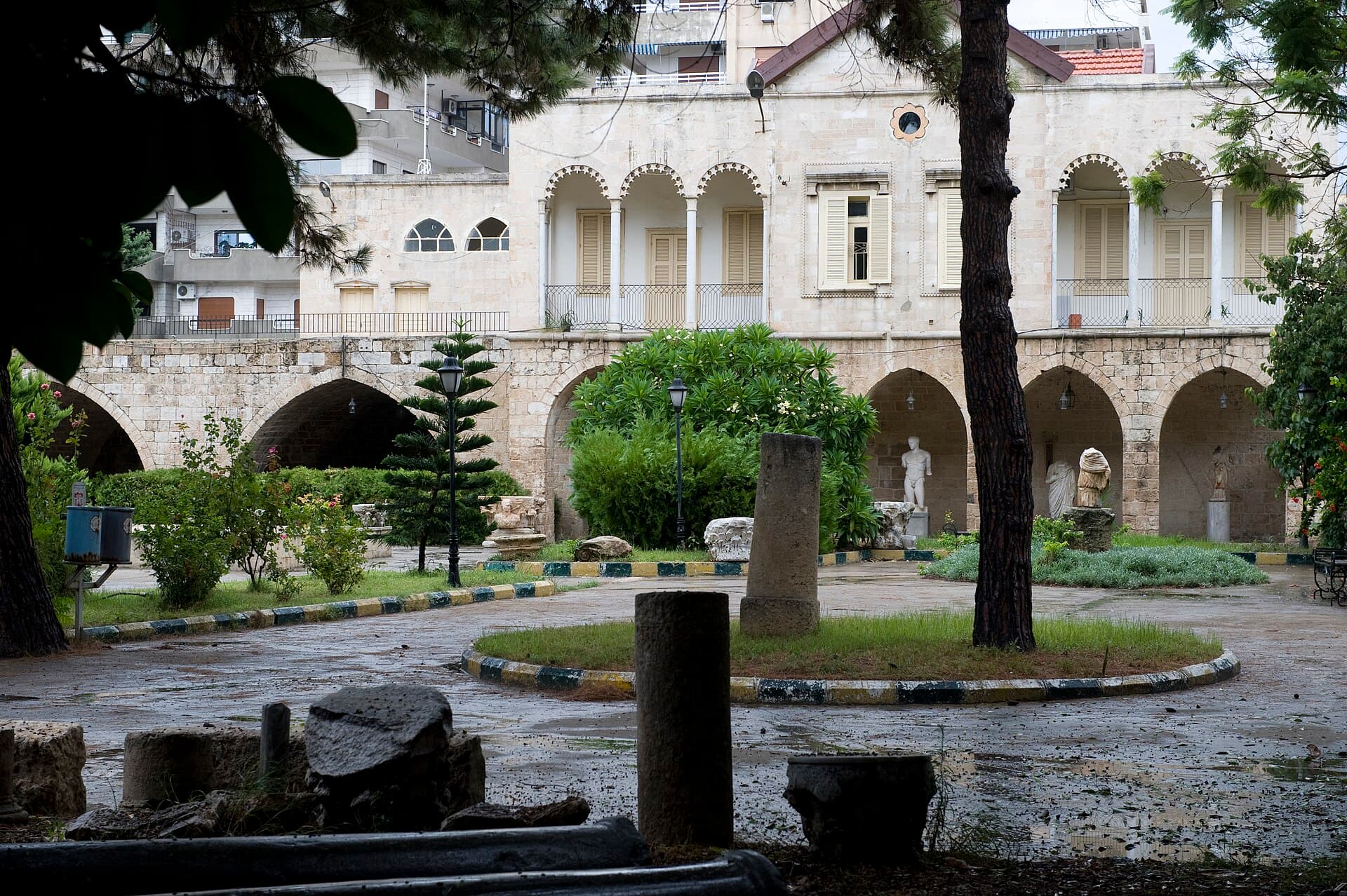 Lazkiye Ulusal Müzesi'nin kervansaray yapısı bahçesinden; kemerli revaklar, sütun gövdeleri ve heykeller