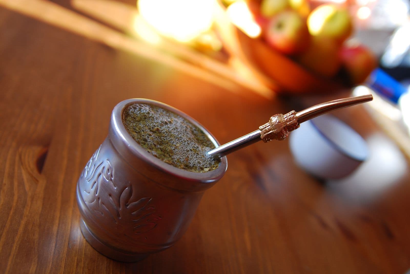 Su kabağına doldurulmuş mate yaprağı ve içine batırılmış metal pipet, ahşap masada