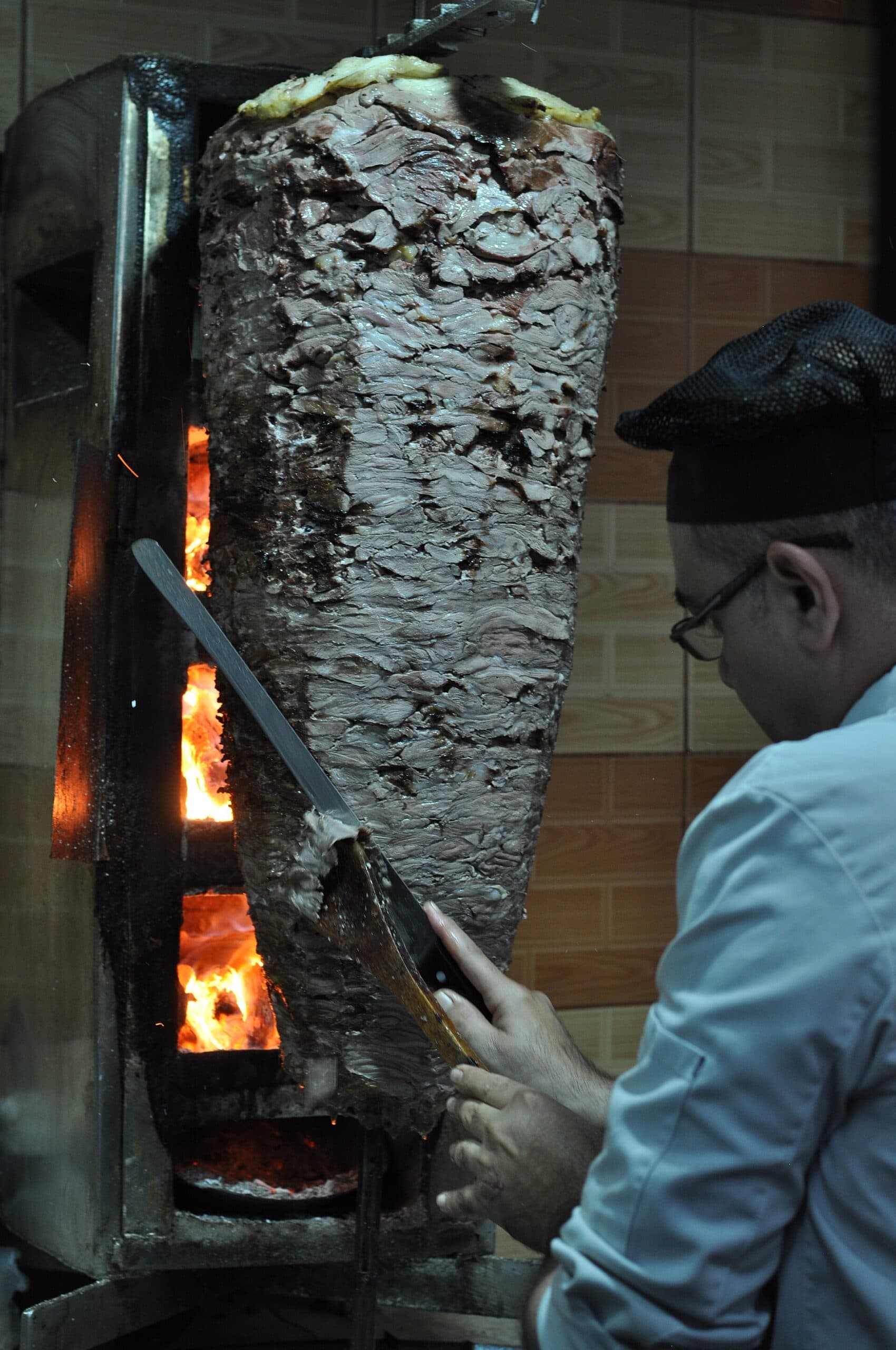 Şam'da ateşin önünde dönen şavurma şişi ve kesim yapan usta