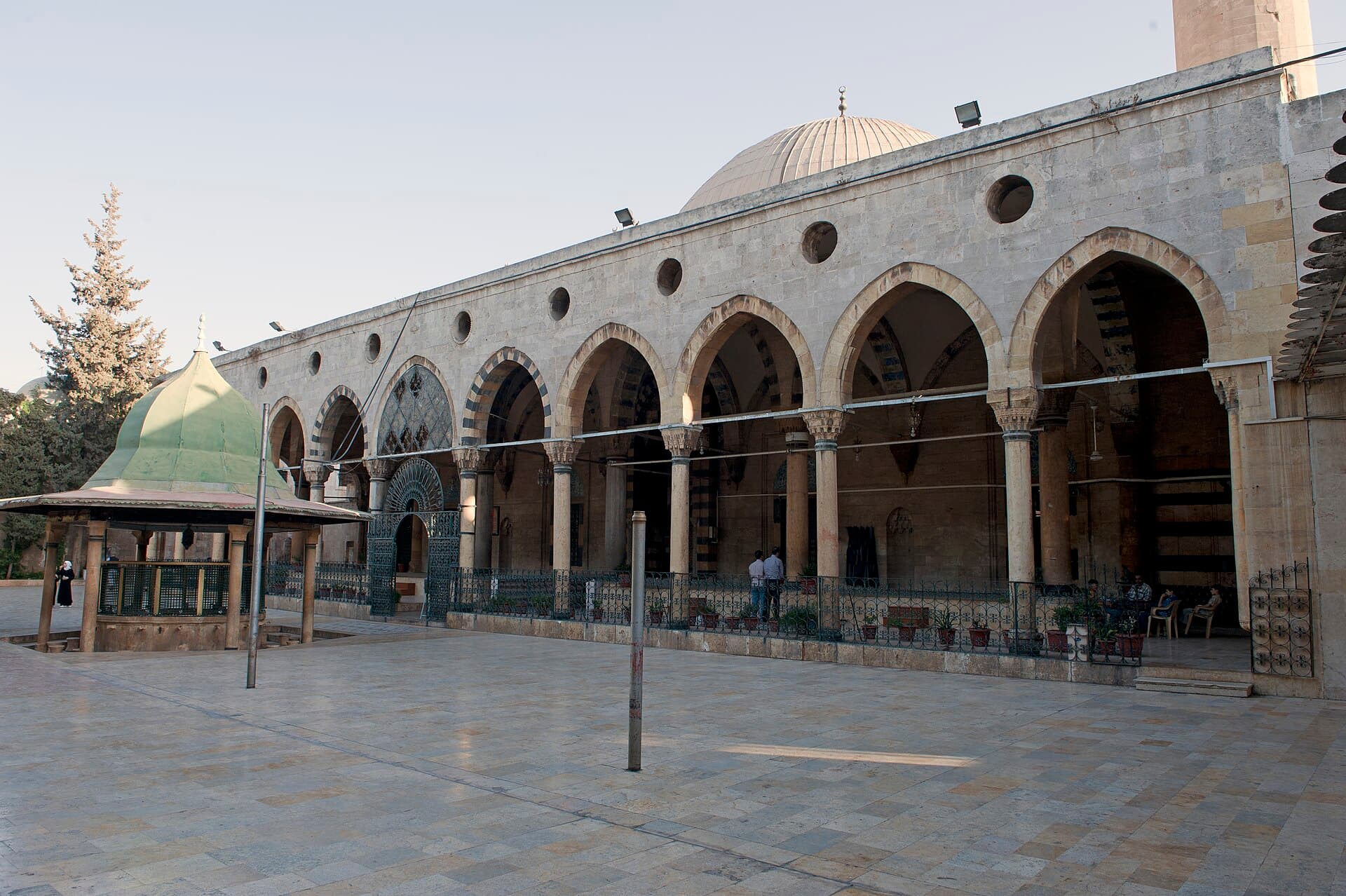 Adiliye Camii'nin avlusu ve çift sıra revakı; sağda kubbe ve minarenin dibi, solda yeşil külahlı abdest köşkü, Halep