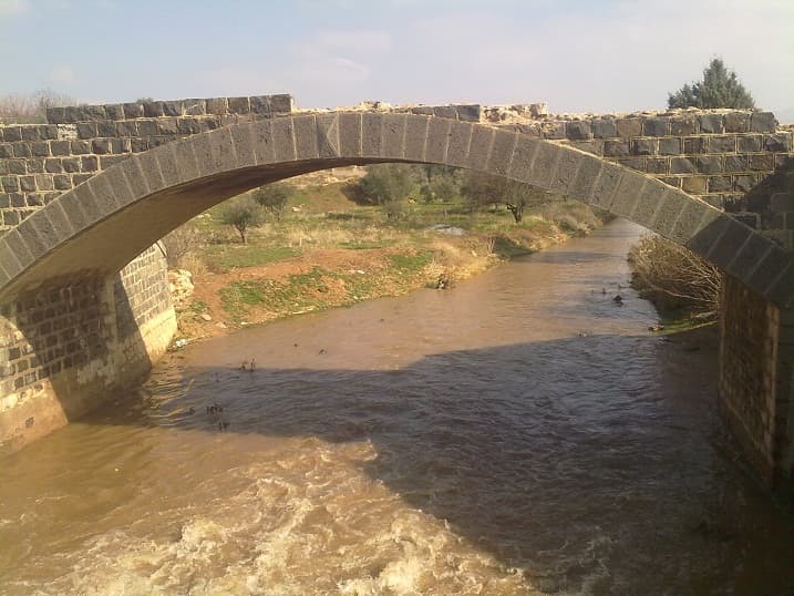 A'vec Nehri'nin bazalt taşından tek kemerli bir köprünün altından geçen bulanık kış suyu