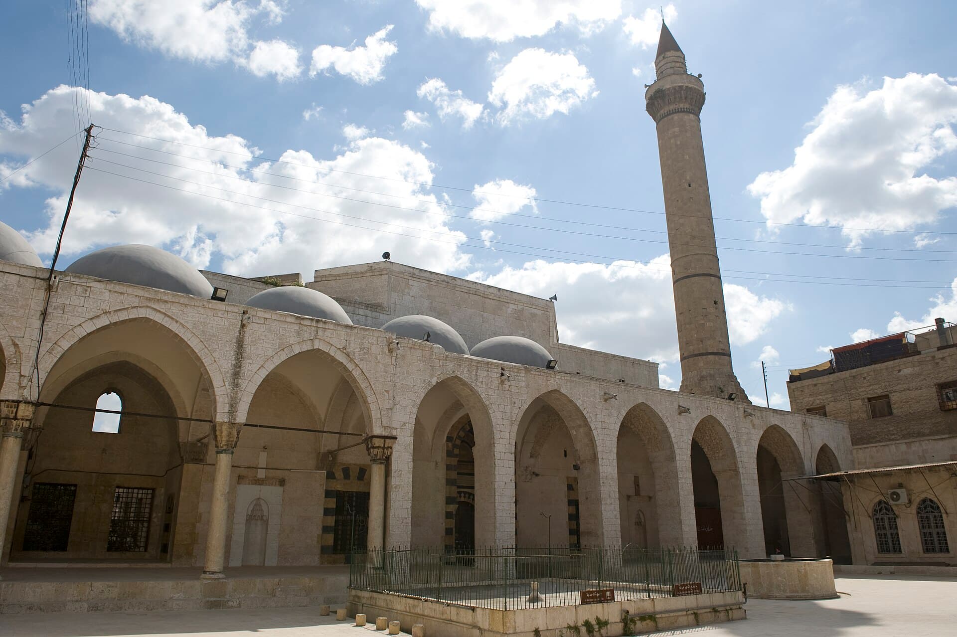 Behramiye Camii'nin revaklı avlusu, revak üstündeki kubbe dizisi ve ince silindirik minare (2009)