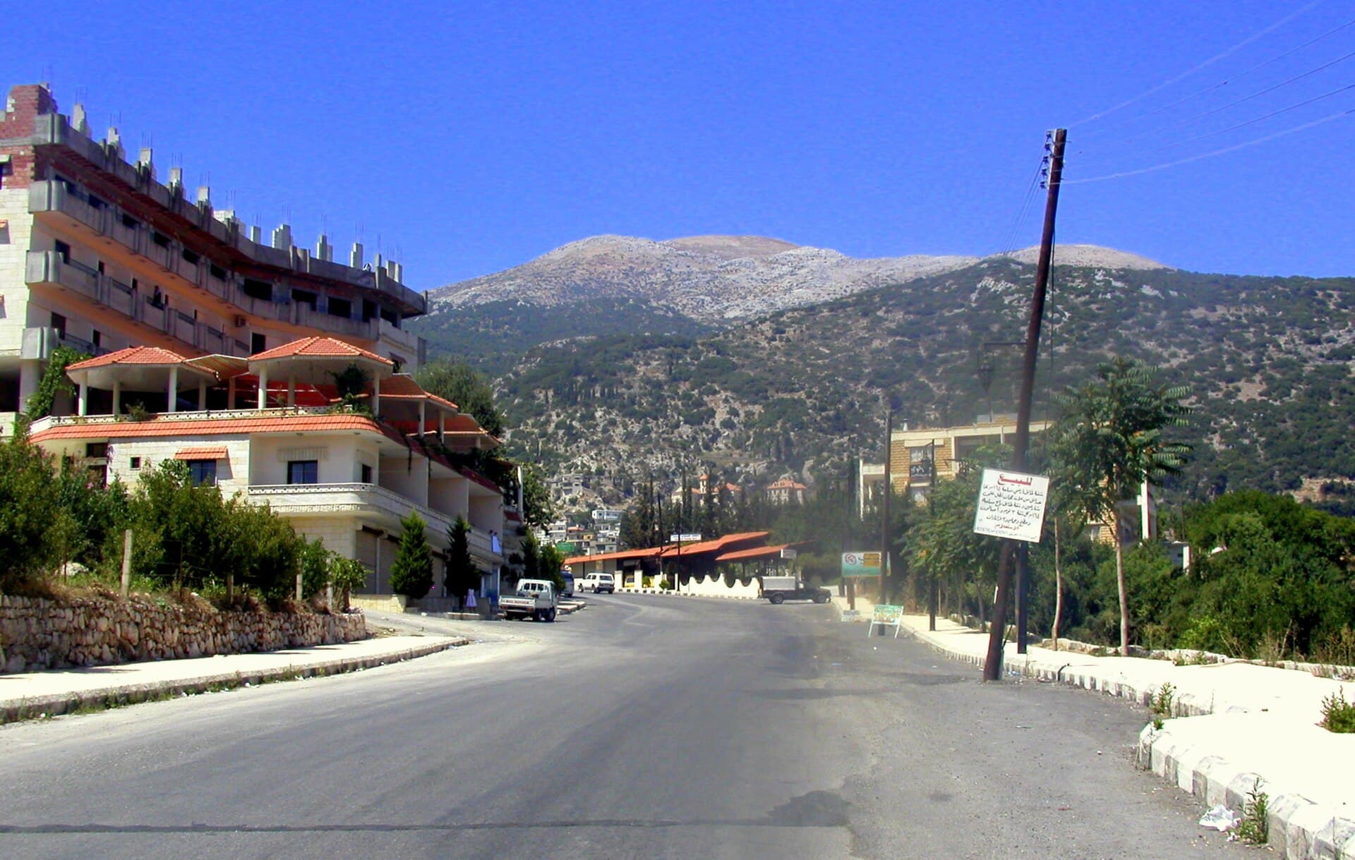 Kessab'ın arkasında yükselen Cebel Akra'nın çıplak tepesi, önde kasabanın yolu ve evleri
