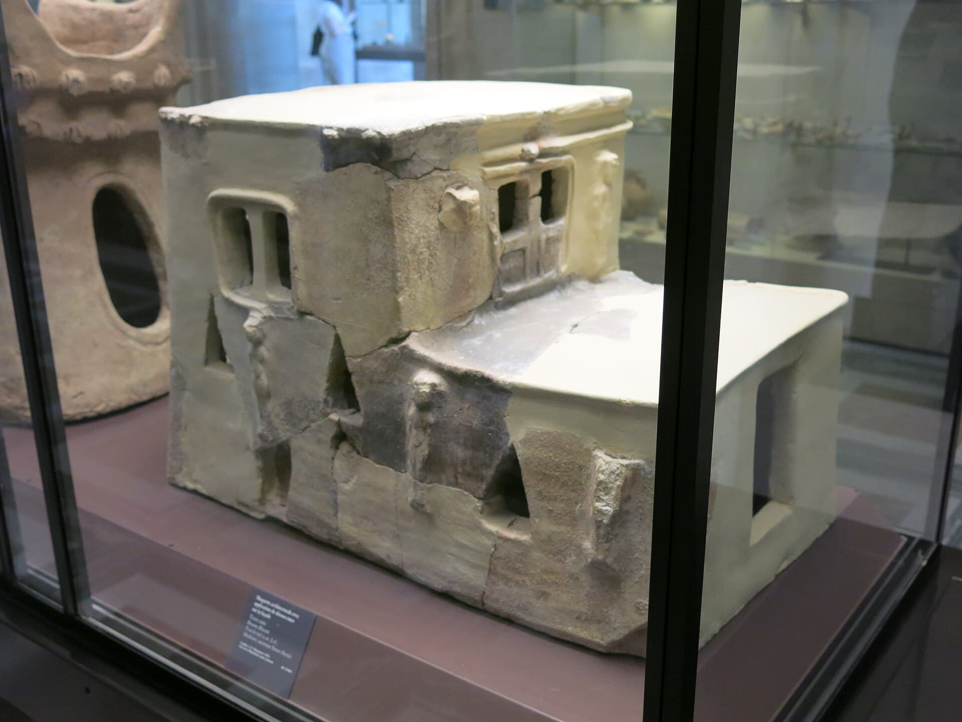 Emar'dan çıkan pişmiş topraktan ev maketi Louvre'da camlı vitrinde: iki bölümlü kademeli ev, pencere açıklıkları ve cephede tanrıça figürleri