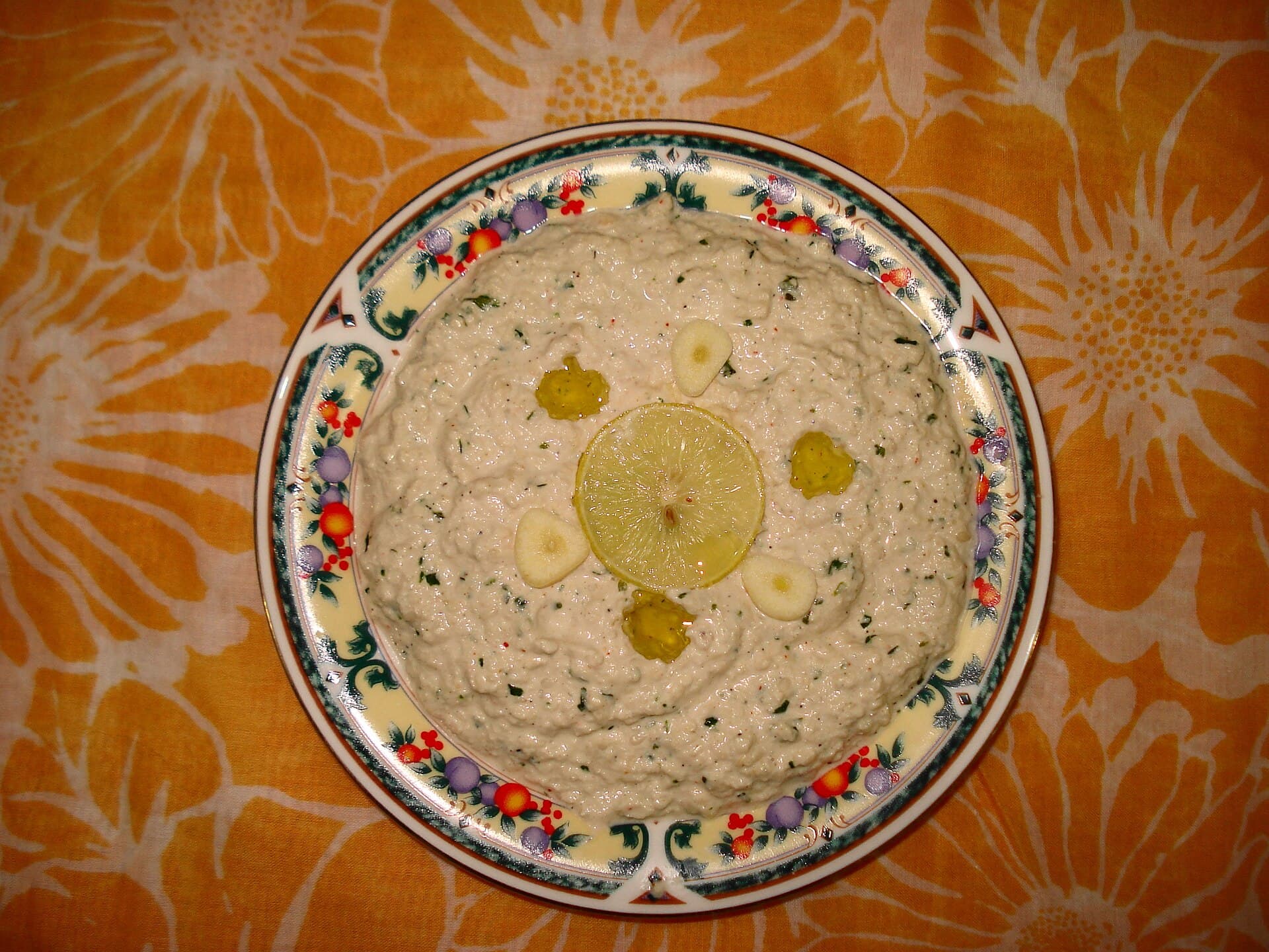 Tahin, limon ve sarımsakla yapılmış koyu kıvamlı tarator sosu, üstünde limon dilimi ve sarımsak yaprakları