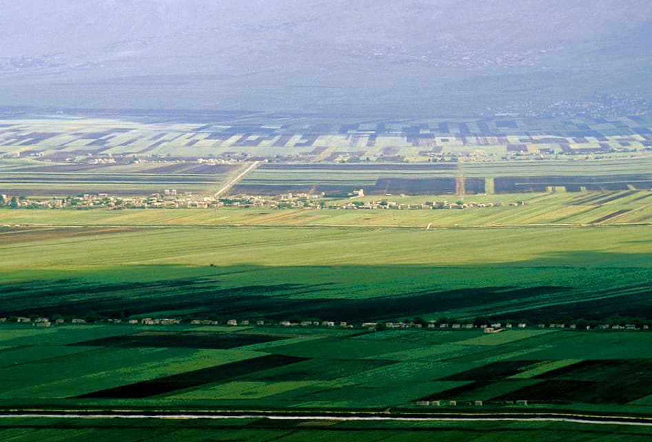 Ğab Ovası'nda kanallarla şeritlere bölünmüş yeşil tarlalar ve köyler, arkada puslu dağ sırası