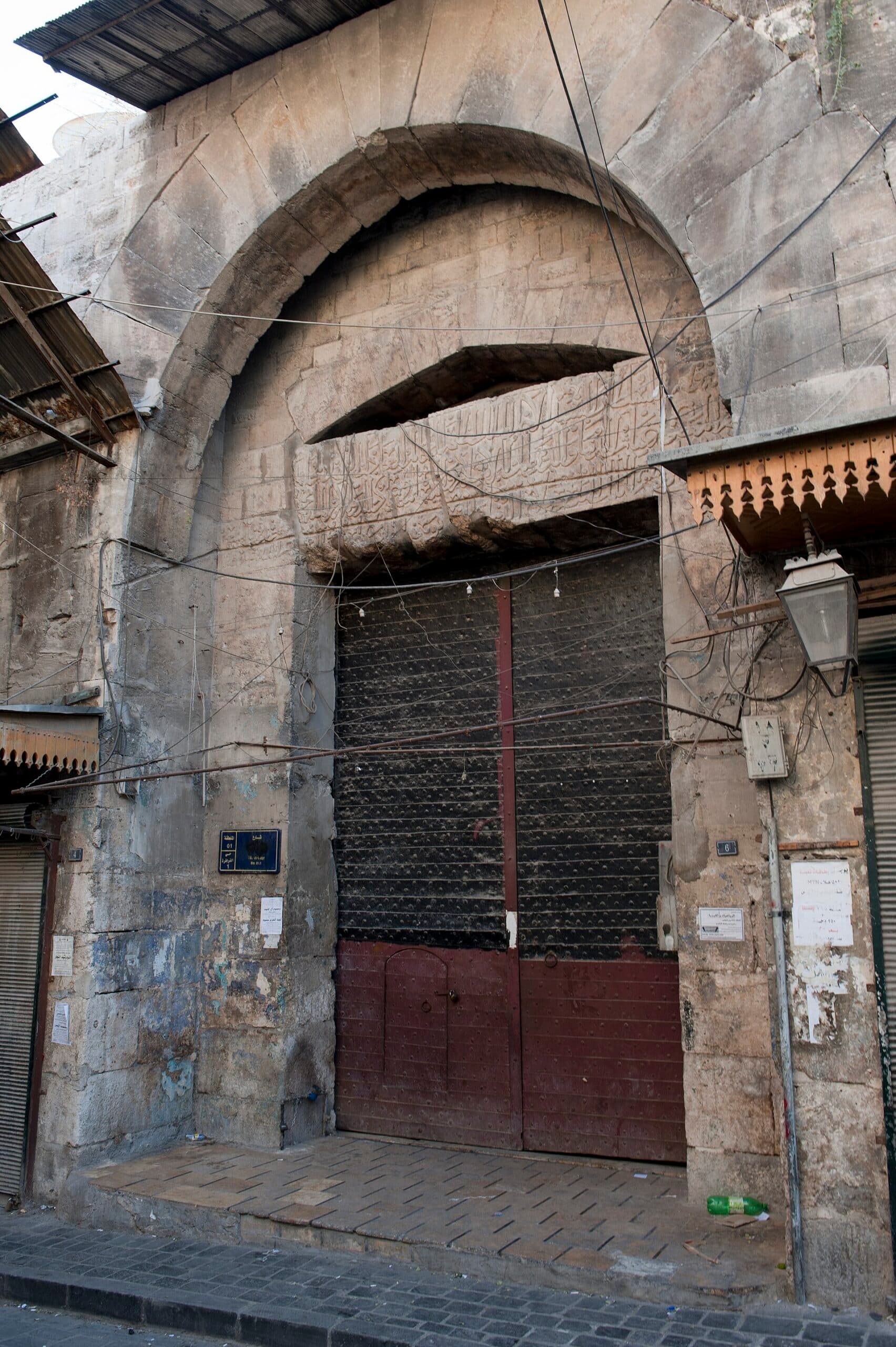 Bab en-Nasr'ın sivri kemerli nişi, kemer içindeki kabartma kitabe kuşağı ve altındaki çivili demir kanatlar