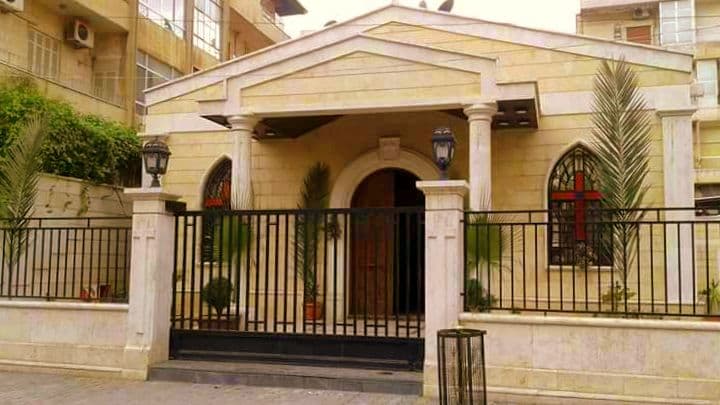 Halep Ulusal Evanjelik Kilisesi'nin Villat mahallesindeki yeni binası; üçgen alınlıklı sütunlu giriş, kemerli ahşap kapı ve demir parmaklık