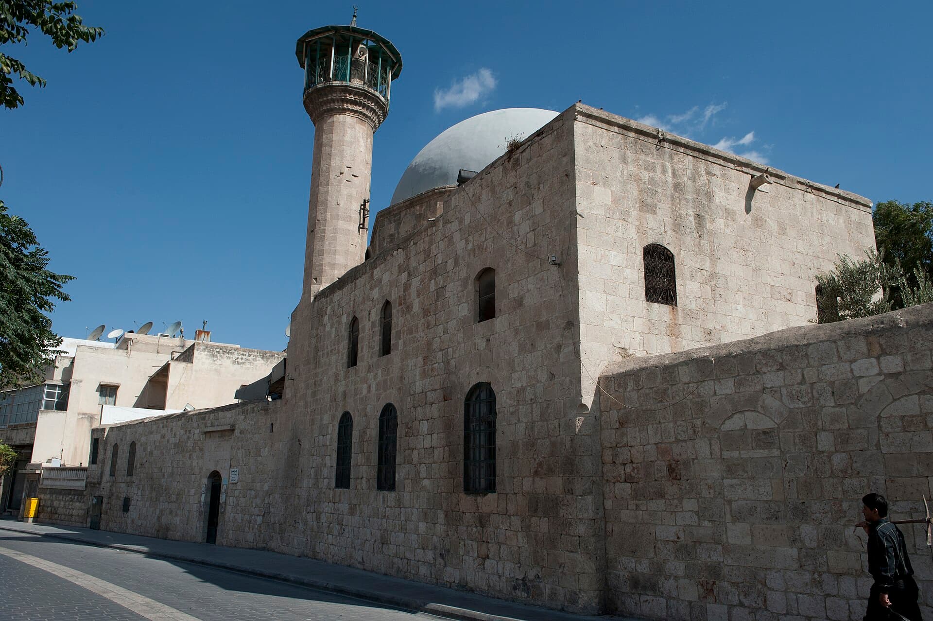 Halep'te Hamevi Camii: kesme taş duvar, kemerli pencereler, sıvalı kubbe ve kafes şerefeli silindirik minare