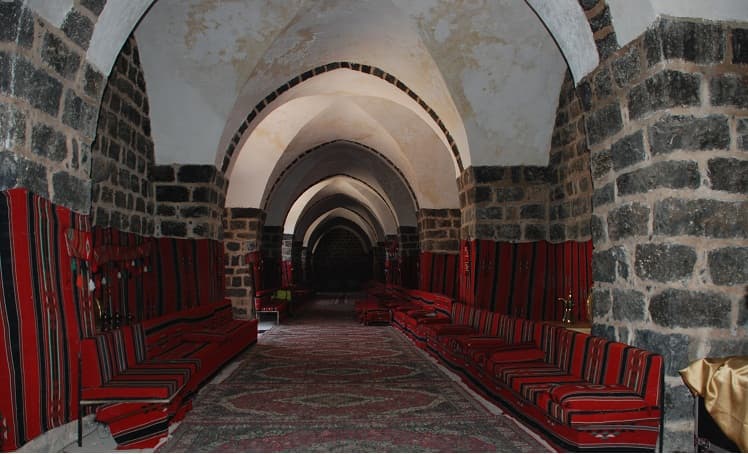 Han Dannun'da bazalt taş duvarlı, beyaz sıvalı tonozlu uzun salon; iki yanda kırmızı çizgili minderler, zeminde halı