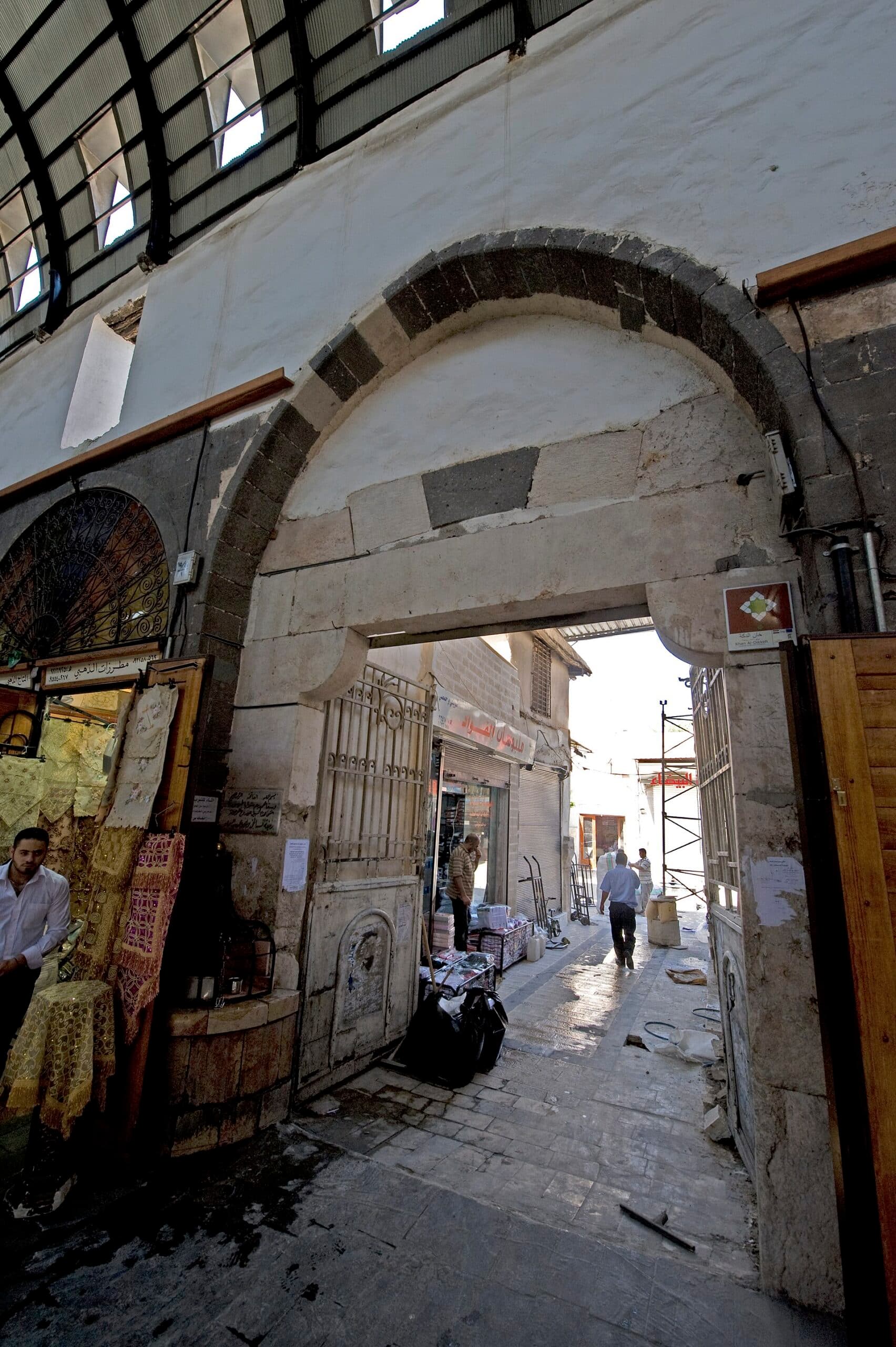 Han ed-Dikke'nin siyah-beyaz taşlı kemerli kapısı, Midhat Paşa Çarşısı'nın sac örtüsü altında