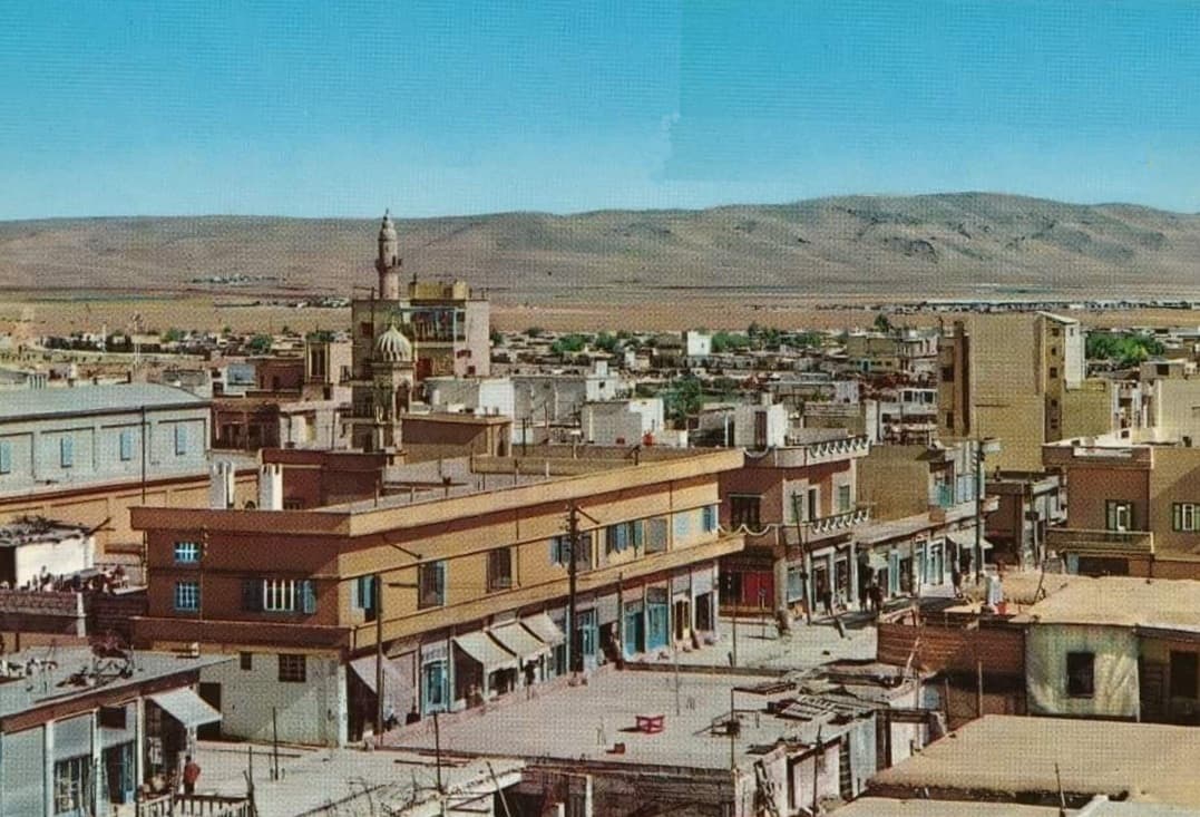 1964'te Kamışlı: damlardan çekilmiş şehir görünümü, ortada minare, ufukta Türkiye tarafındaki tepeler