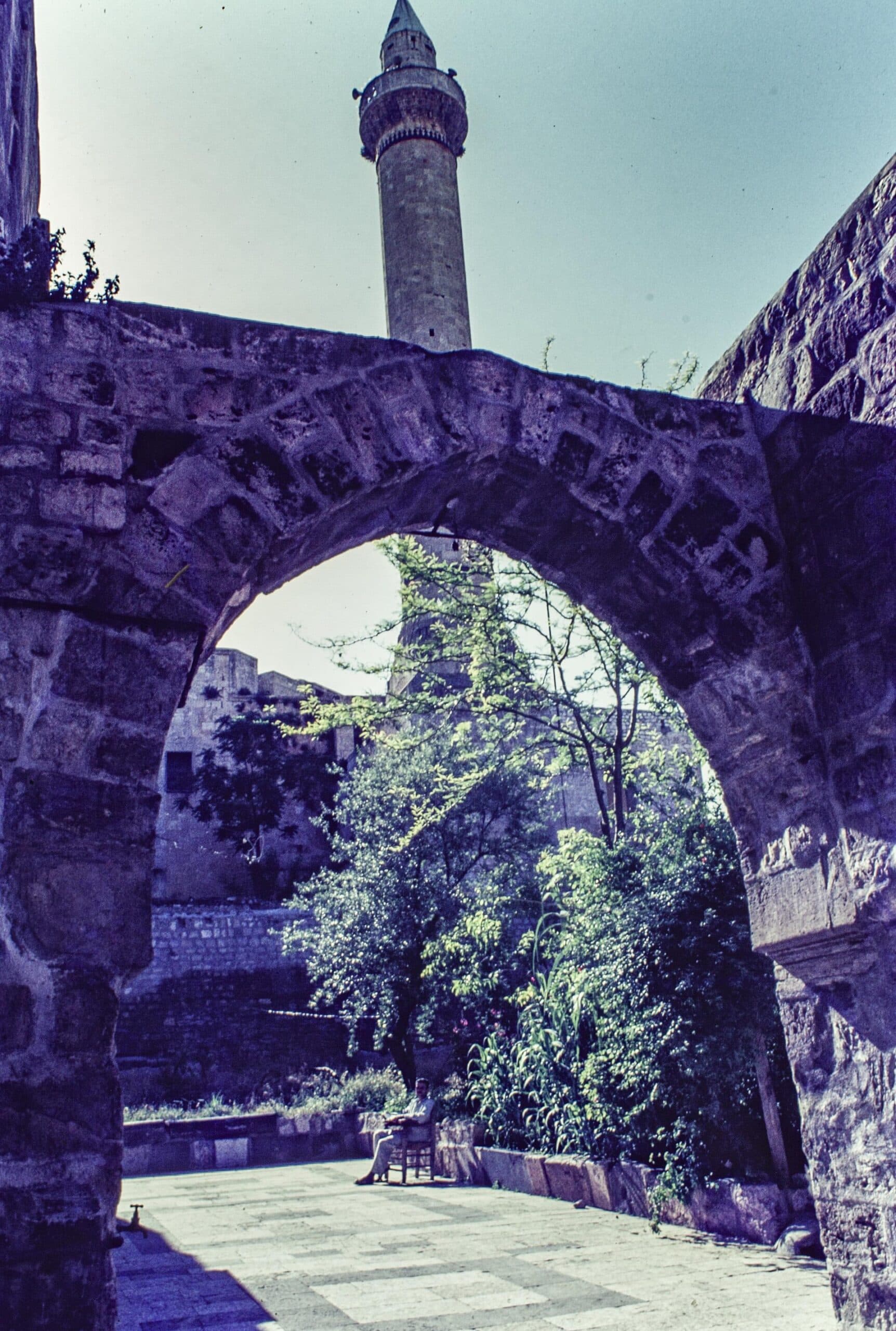 Mukaddemiyye Medresesi'nin avlusuna açılan sivri taş kemer; kemerin ardında ağaçlı avlu ve bir minare