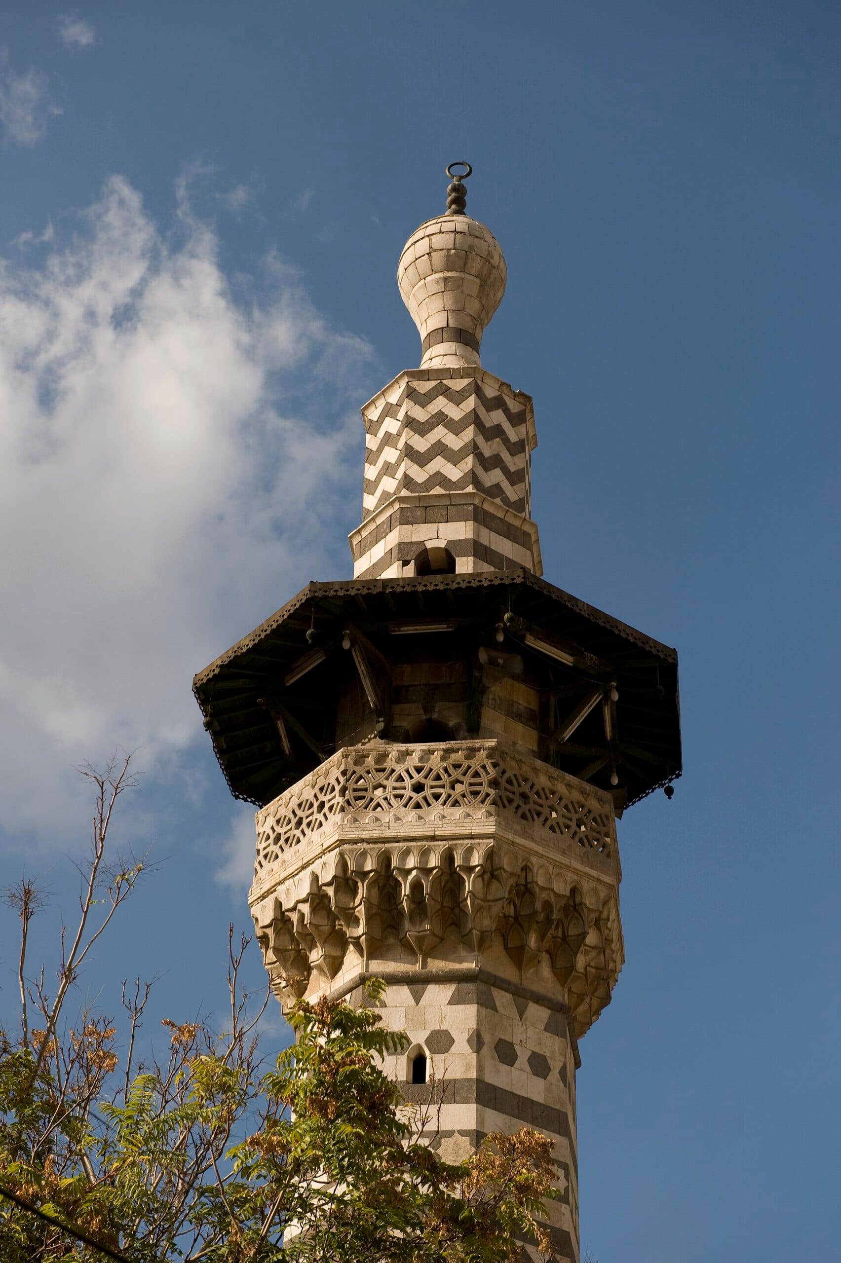 Safercelani Camii'nin siyah beyaz taş sekizgen minaresi; ahşap saçak, zikzak kuşak ve soğan biçimli tepe