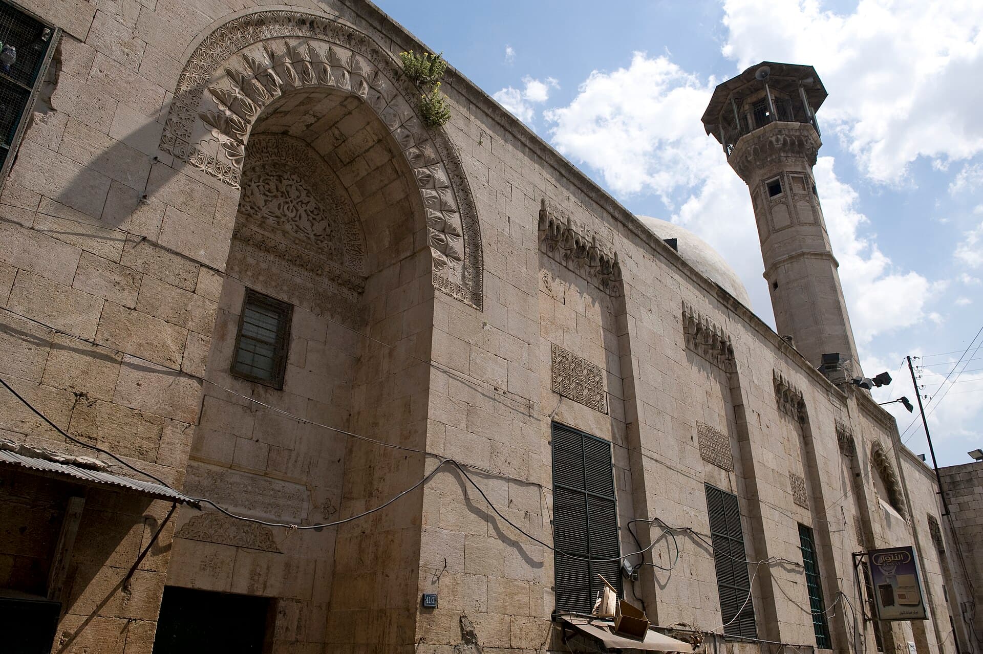 Saravi Camii'nin sokağa bakan taş cephesi: mukarnaslı taç kapı kemeri, yazıt panoları ve arkada sekizgen minare