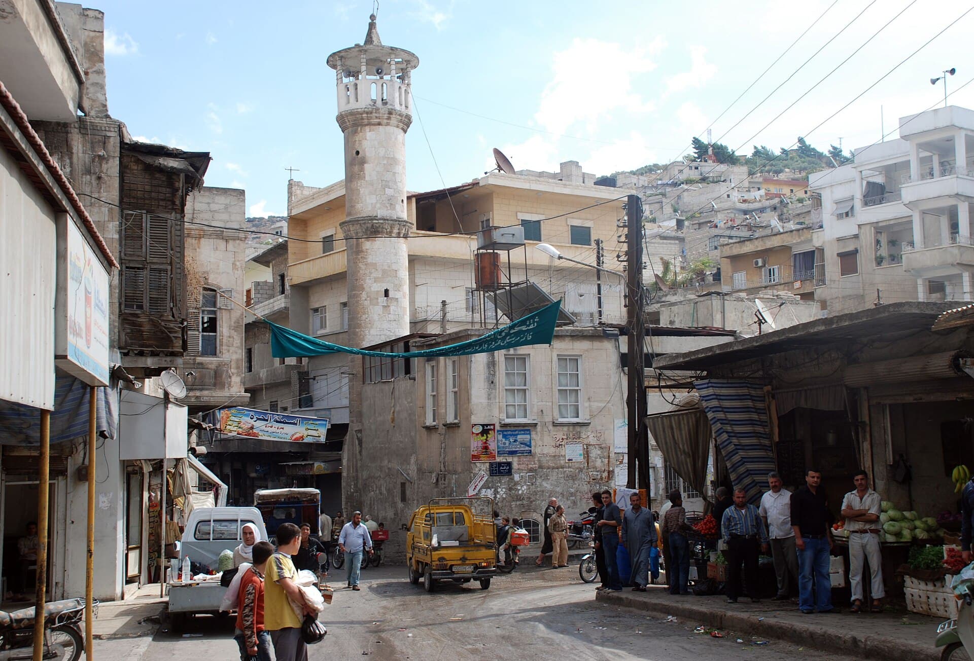 Selkin kasaba merkezi: taş minareli cami, önünde dükkânlar ve sokak, arkada yamaca tırmanan evler, 2009