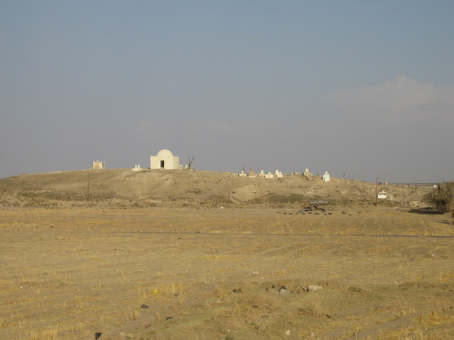 Tell Fekheriye höyüğü, tepesindeki kubbeli türbe ve mezarlıkla doğudan görünüşü