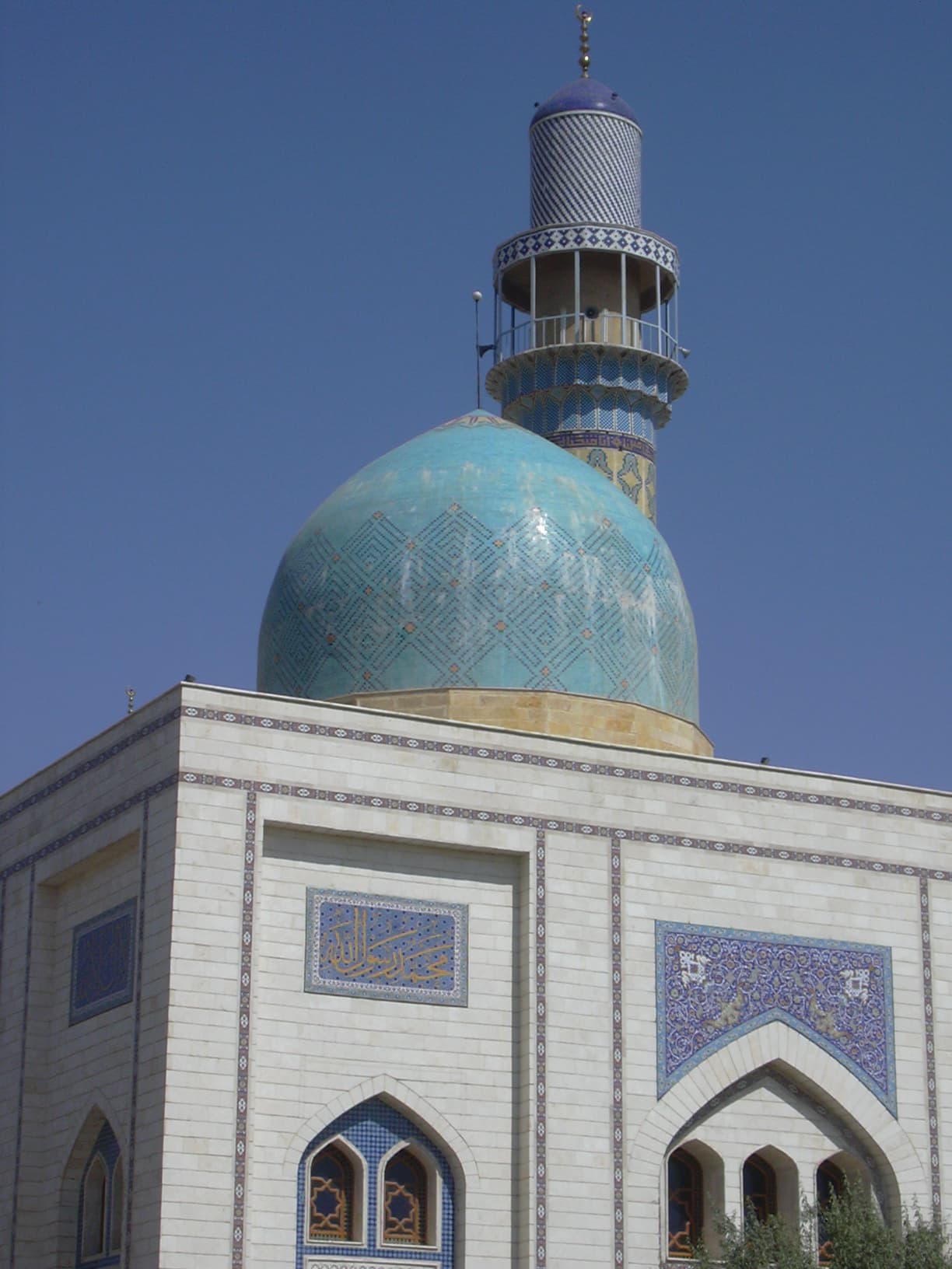 Rakka'da Üveys el-Karanî külliyesinin turkuaz çinili kubbesi, çini kaplı minaresi ve hat panolu beyaz taş cephesi, 2006; yapı 2014'te yıkıldı
