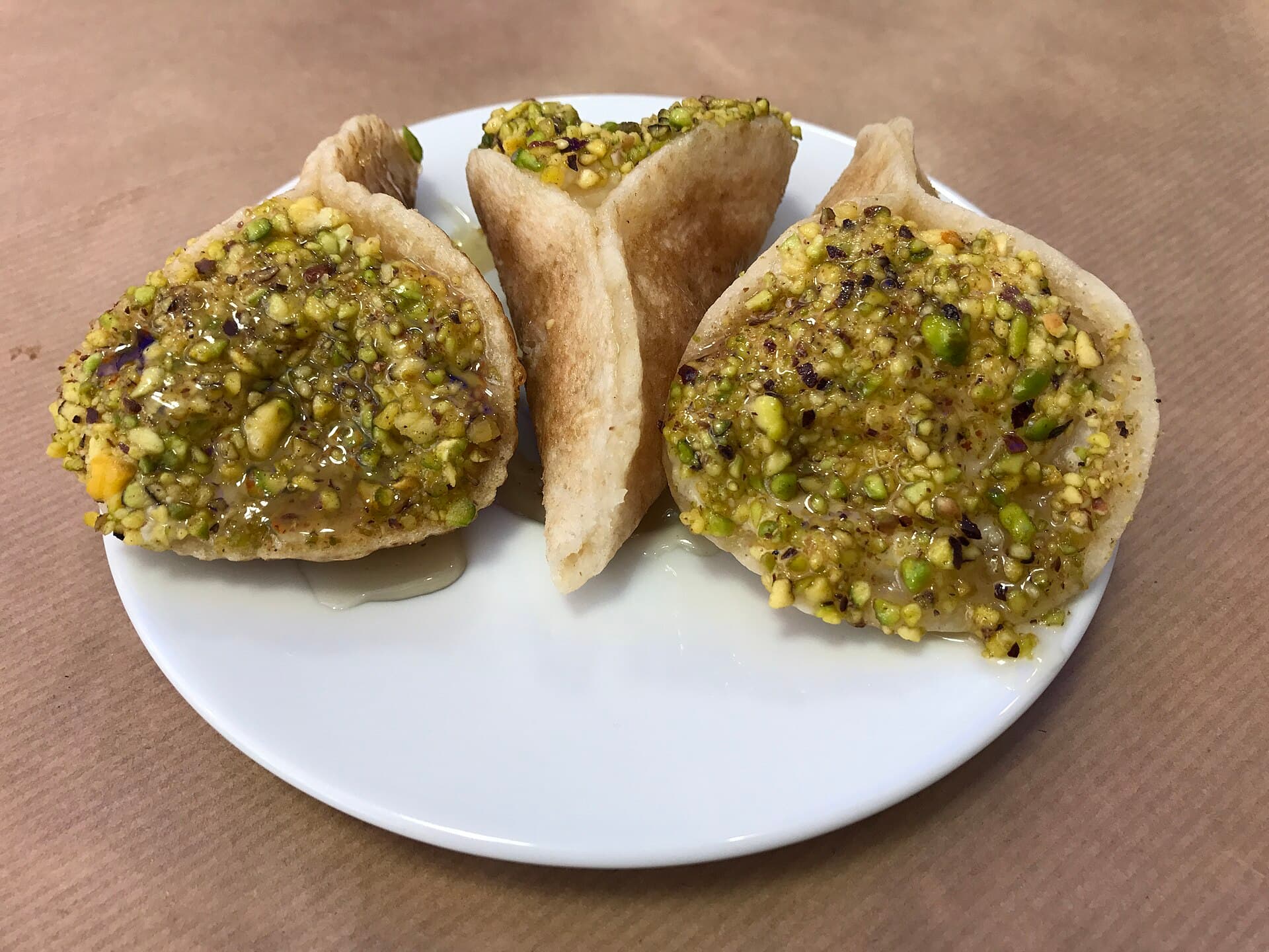 Kaymakla doldurulup fıstığa bulanmış açık katayef ve yanında katlanmış bir tanesi