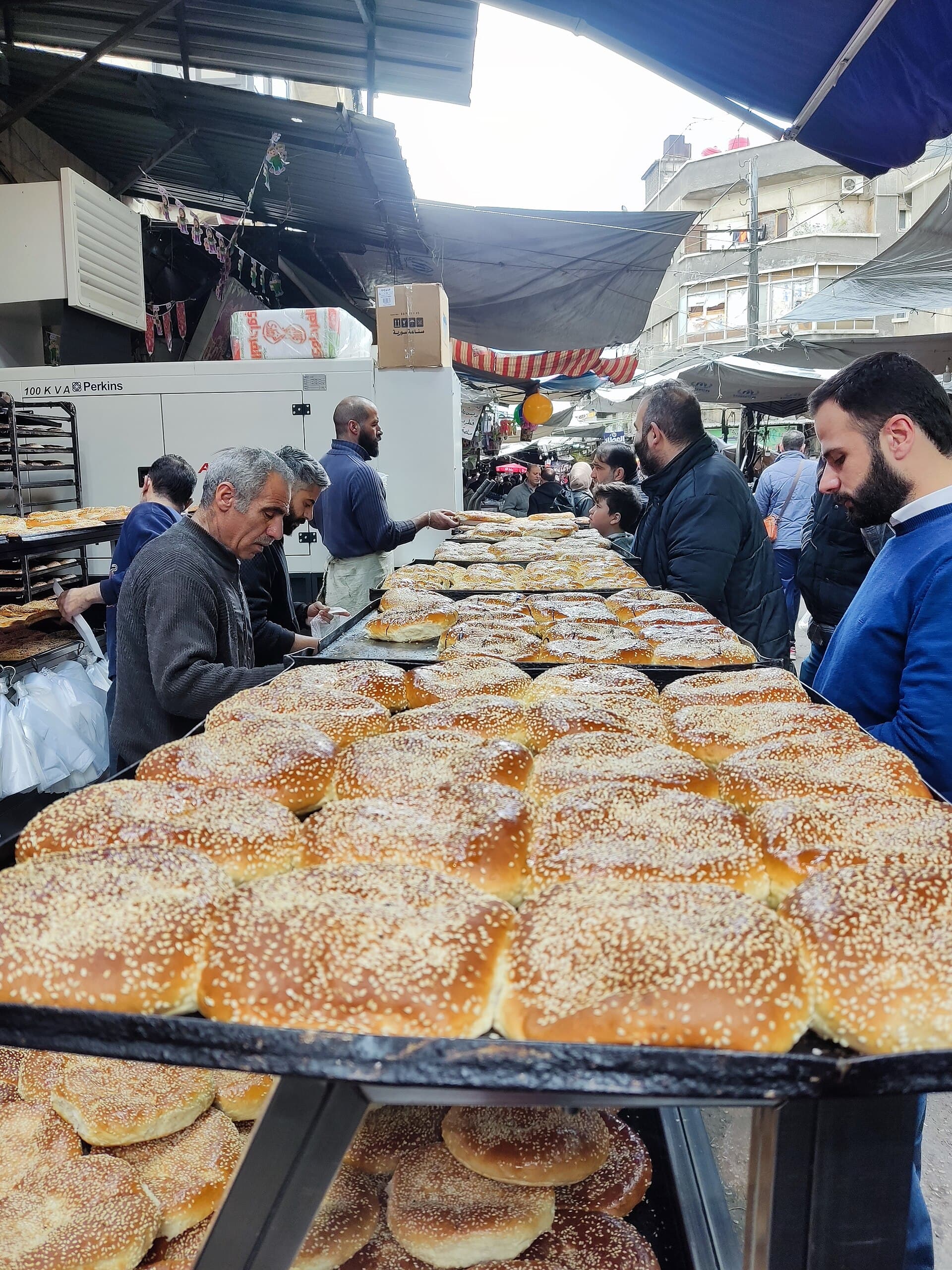 Sokak tezgâhında tepsiler dolusu susamlı maaruk ve çevresinde bekleyen müşteriler