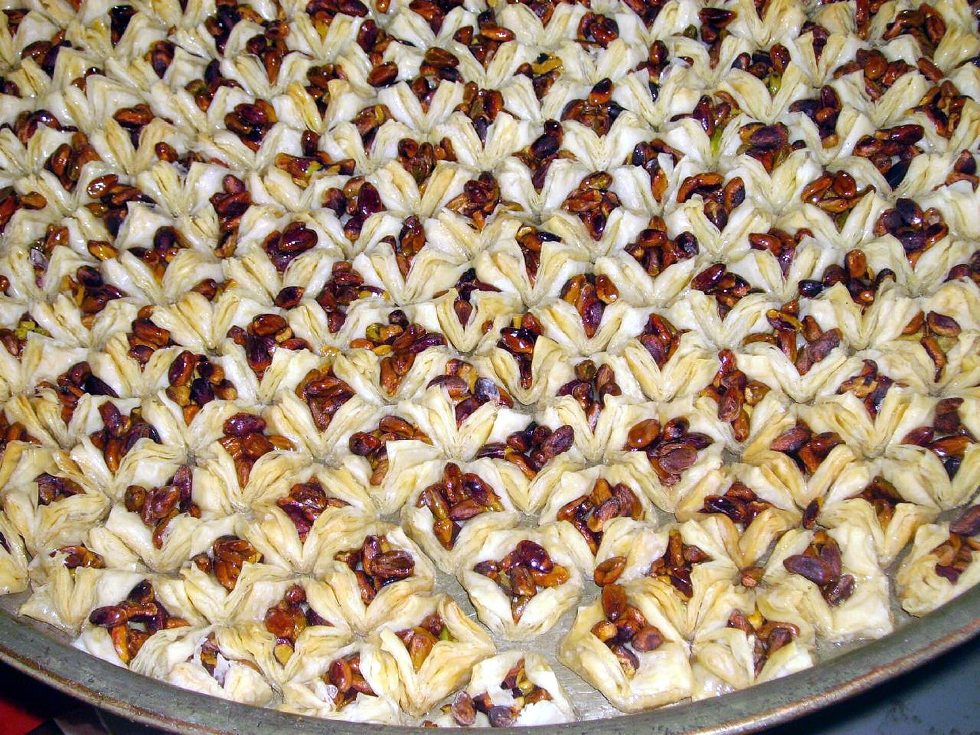 Şam'da bir tatlıcının tepsisinde sıra sıra dizilmiş, fıstıkla doldurulmuş baklava