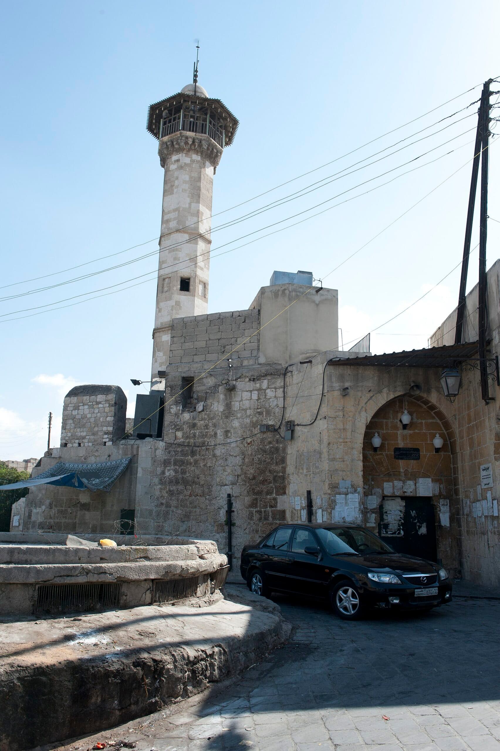 Bankusa Camii'nin taş minaresi ve sivri kemerli girişi; minarenin üstünde sütunlu açık şerefe katı