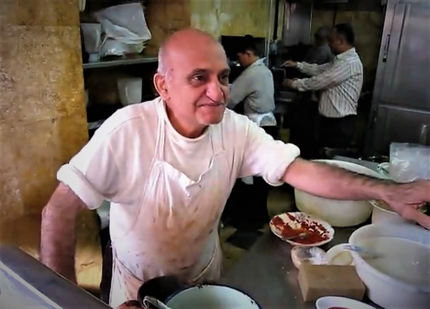 Halep Cdeyde'de Ebu Abdo fulcusunun tezgâhı; önlüklü usta, arkada çalışanlar, kâselerde ful ve bir tabak biber salçası