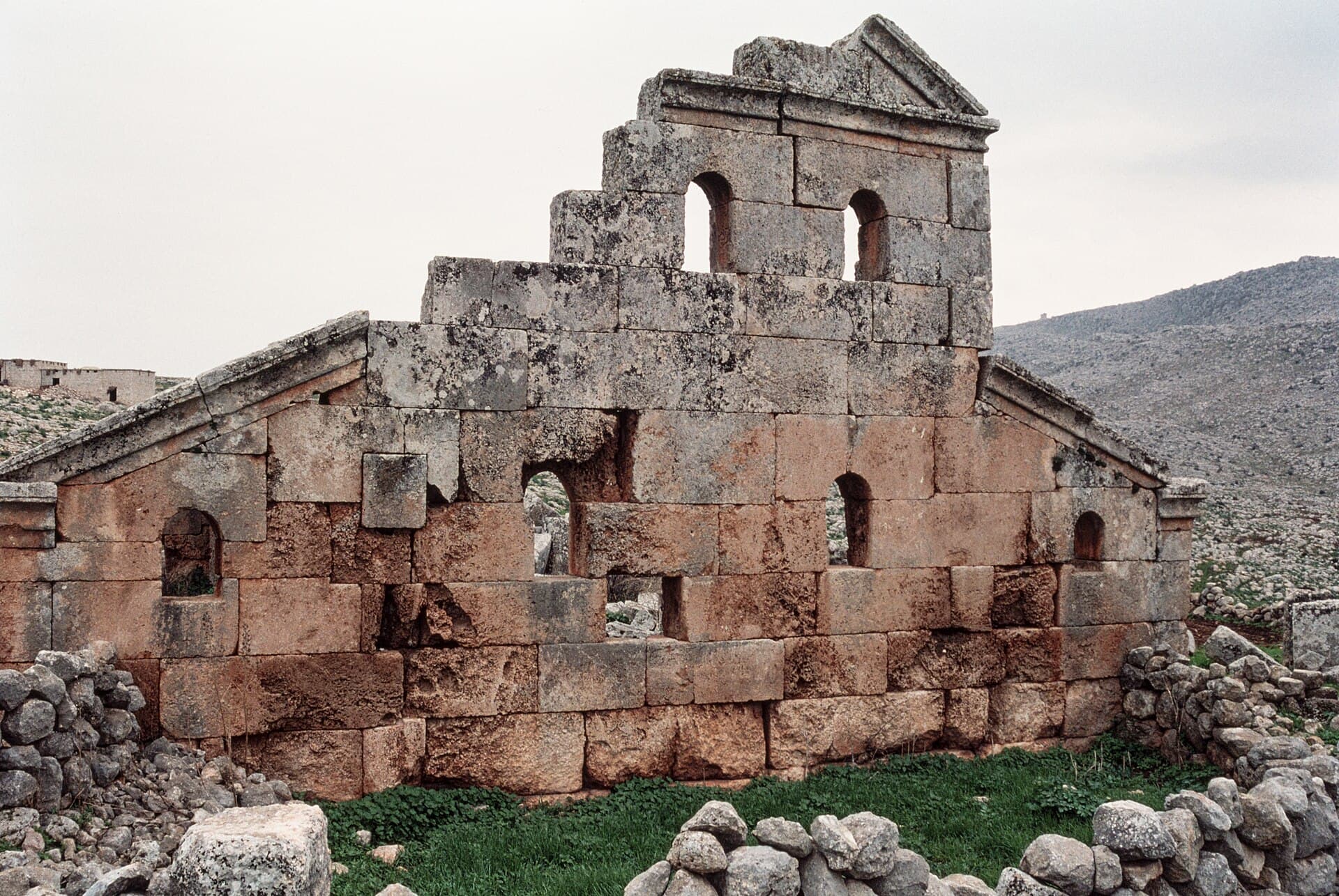 Hırbet el-Hatib'de 473 tarihli kilisenin batı cephesi: üçgen alınlıklı orta bölüm, kemerli pencereler ve iri kesme taş duvar, arkada taşlık yamaç