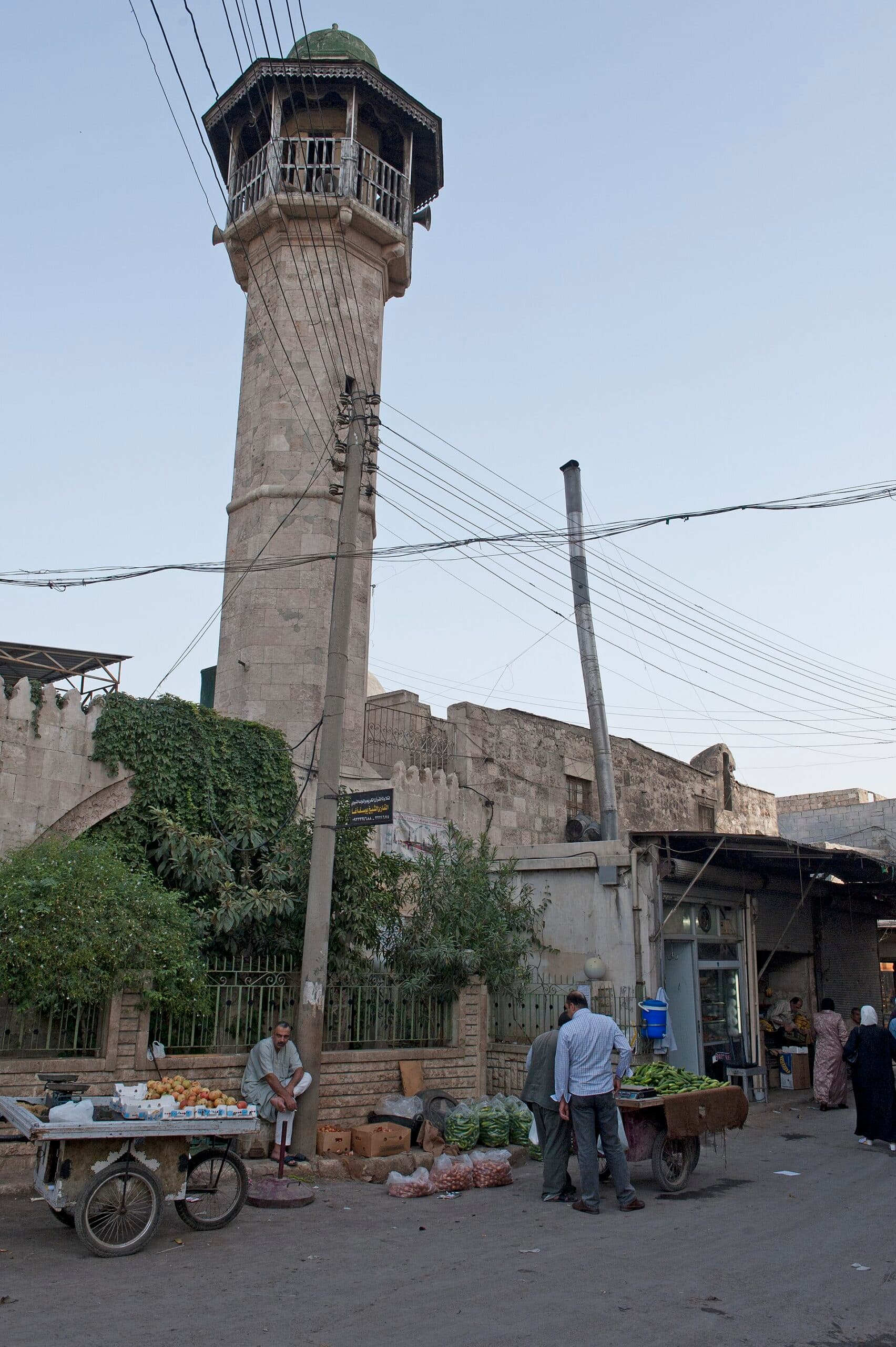 Kastal el-Harami Camii'nin sekizgen minaresi; altında sebze arabalarının dizildiği mahalle sokağı