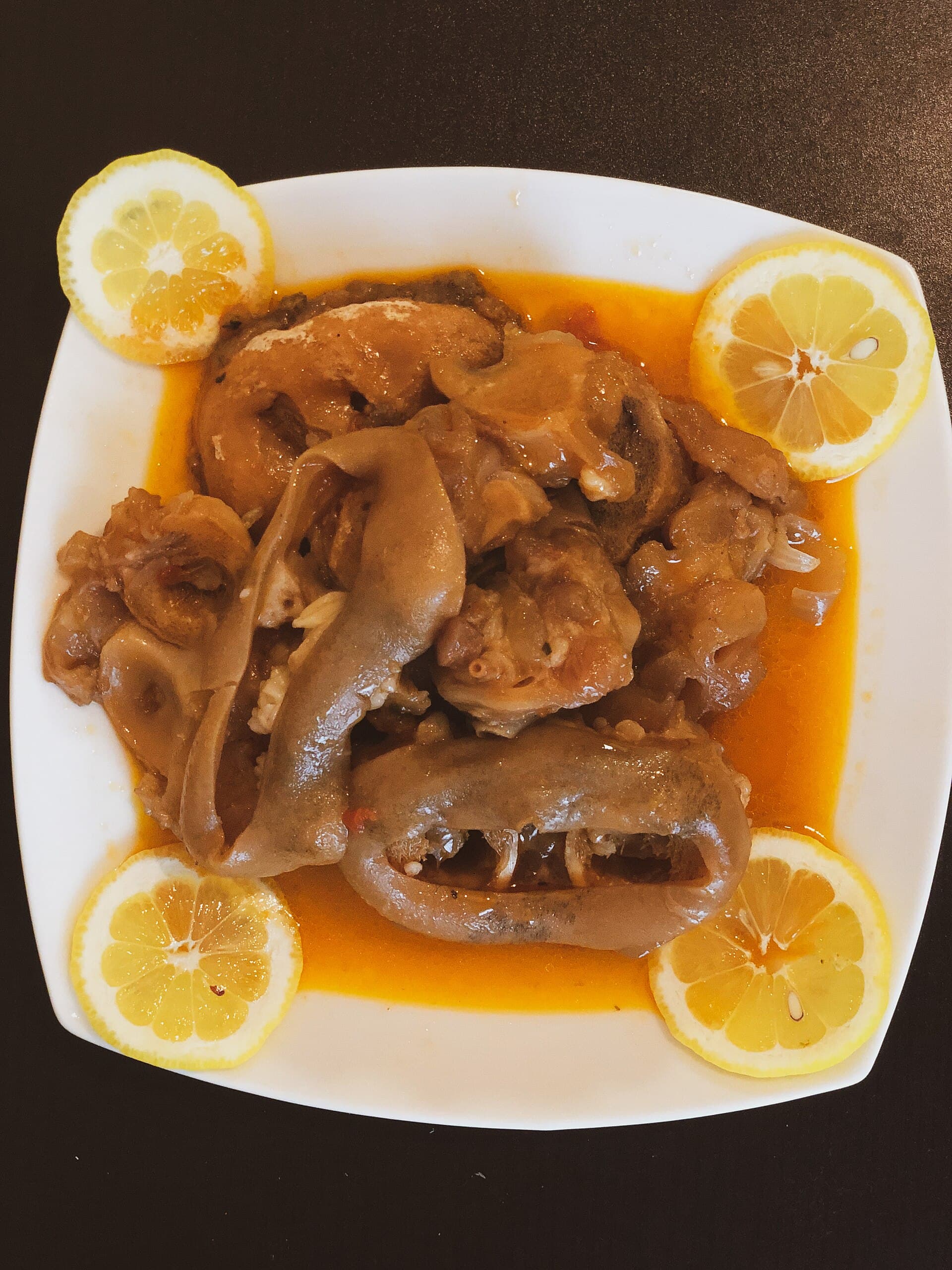 Derin bir tabakta haşlanmış koyun paçası, kendi suyunda ve limon dilimleriyle