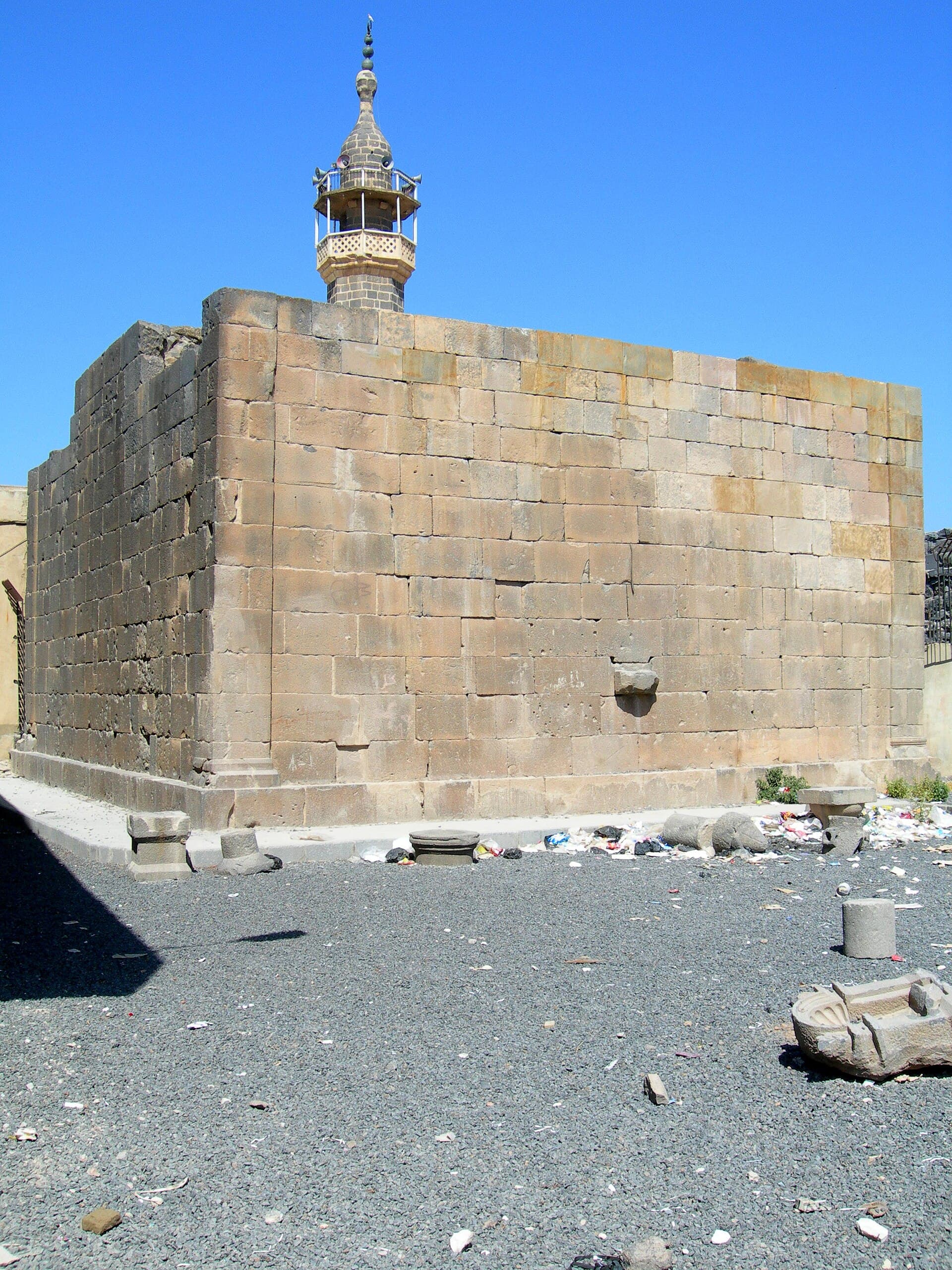 Sanemeyn'deki Roma tapınağının taş gövdesi ve arkasında Osmanlı minaresi.